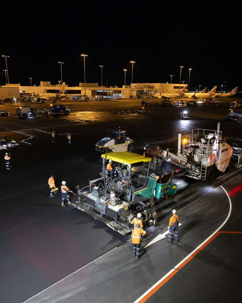Night asphalt paving crew working on an airport runway