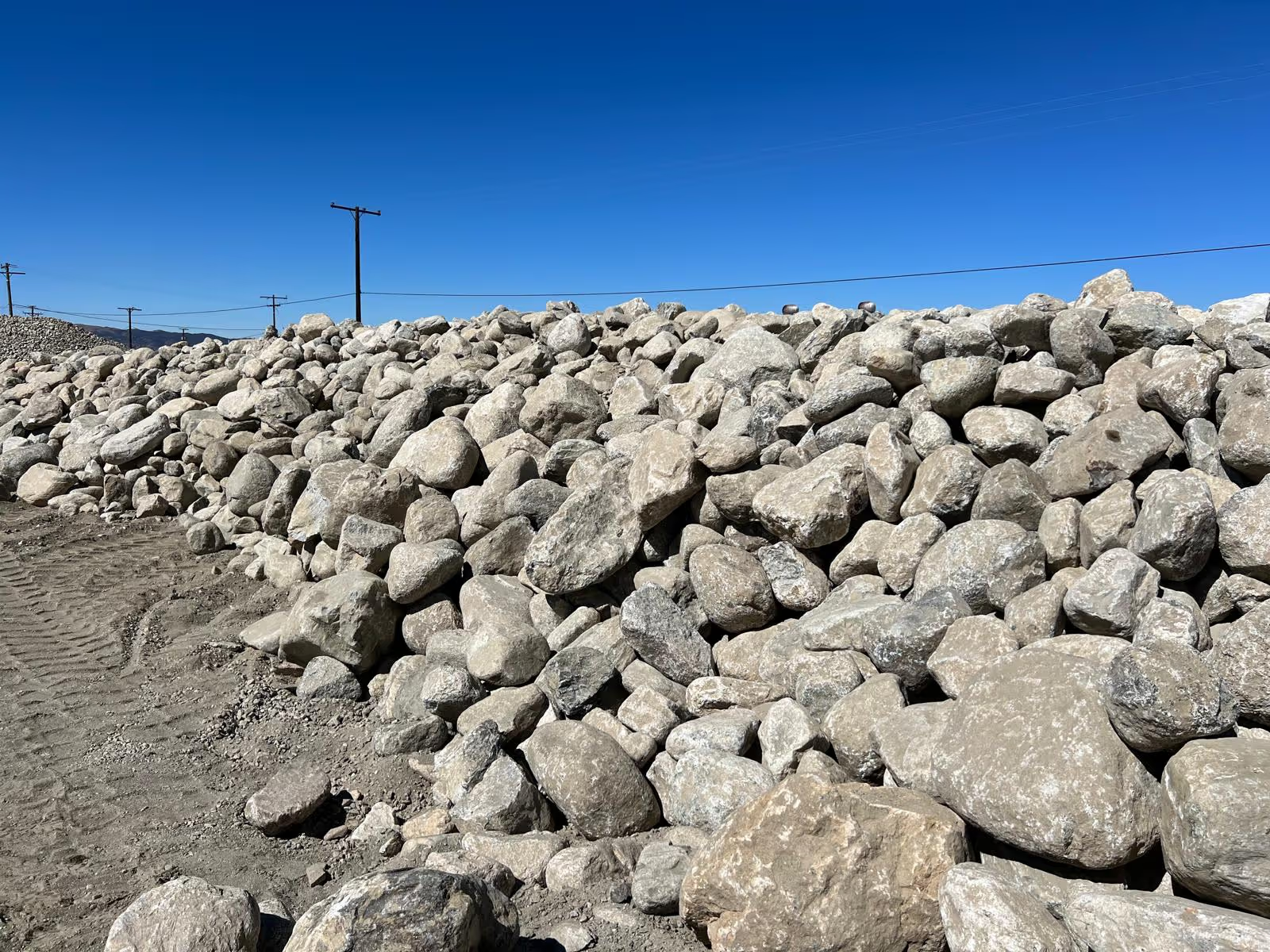Large pile of grey rip rap boulders under a blue sky
