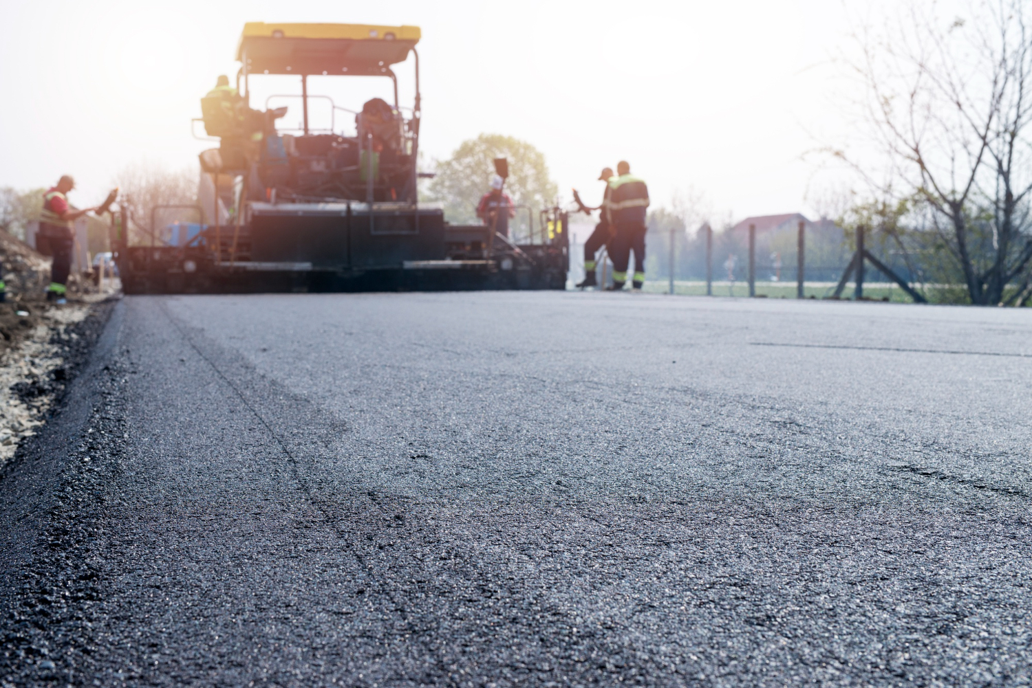 Asphalt paver and crew laying warm mix asphalt